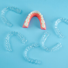 Invisible dental teeth brackets tooth aligners on blue background. Plastic braces dentistry retainers to straighten teeth