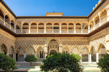 Fototapeta premium The Alcazar of Seville, historic royal palace in Seville town, Andalusia, Spain. Ornate palace courtyard with intricate arches and lush greenery. A beautiful example of historical architecture.