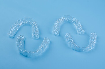 Invisible dental teeth brackets tooth aligners on blue background. Plastic braces dentistry...