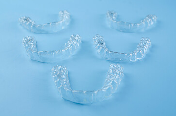 Invisible dental teeth brackets tooth aligners on blue background. Plastic braces dentistry...