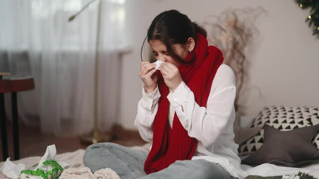 Sick unhealthy young indian woman with warm scarf coughing sneezing and having severe headache temperature at home Sad tired girl with flu virus symptom at cold season indoors