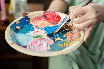 Young artist mixing vibrant colors on a palette with a brush, showcasing creativity and artistic expression
