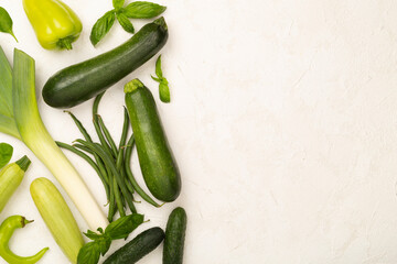 Different fresh green vegetables on concrete background, top view