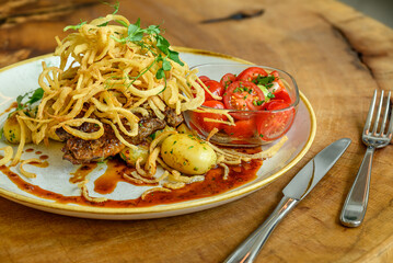 Gourmet Steak Dish with Fried Onions and Tomato Salad
