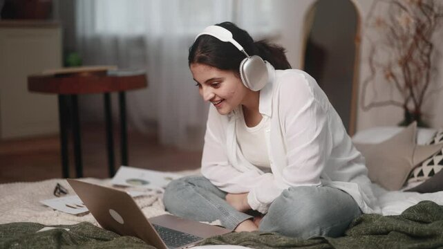 Excited focused motivated young indian woman student listening interesting exciting online lecture with enthusiasm on laptop computer sitting on bed at home Distance remote education concept	