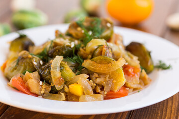 Brussel sprouts cooked with vegetables, on a wooden table