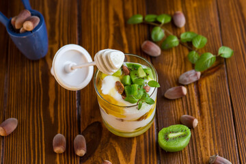 homemade yogurt with kiwi, honey and nuts in a glass on a wooden table