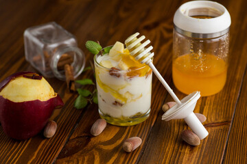 sweet homemade yogurt in a glass with apples, nuts and honey