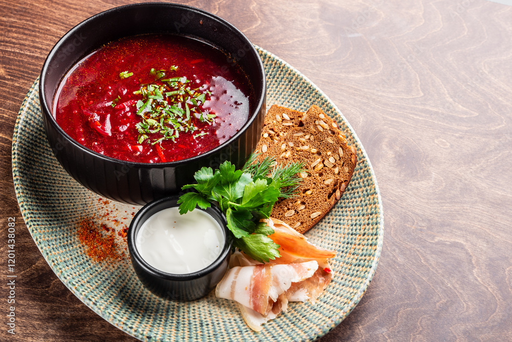 Wall mural A traditional bowl of borscht served with sour cream, fresh herbs, dark bread, and cured meat on a decorative plate, set on a wooden table. A vibrant and hearty meal.