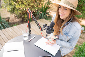 Attractive woman recording radio podcast - Young girl talking during live stream session outdoor....