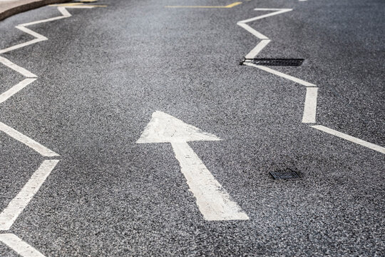 This image features a close-up of a zigzagged road marking directing traffic, emphasizing urban navigation and the importance of transportation in city living.