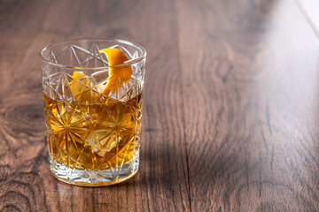 Old fashioned cocktail garnished with orange on wooden table. Copy space