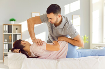 Young woman lying on couch, having chiropractic back adjustment. Doctor or physiotherapist...