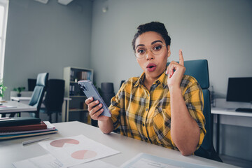 Photo of attractive young woman hold device eureka idea wear yellow plaid shirt comfortable modern office room interior indoors workspace