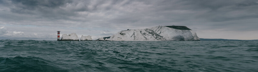 A rocky island is visible in the distance, with a lighthouse in the foreground