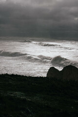 A rocky shoreline with a dark sky and crashing waves