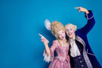 Playful couple in costumes posing against a vibrant blue background, showcasing an enchanting...