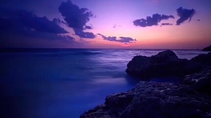 Obraz premium Serene twilight seascape with rocks and purple sunset sky.