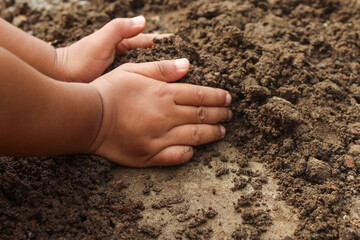 Close up of a little boy's hands playing with dirt or sand. child playing outdoors