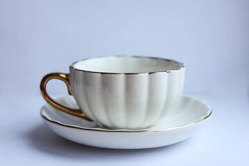 white and gold cup of tea with saucer on a white background.