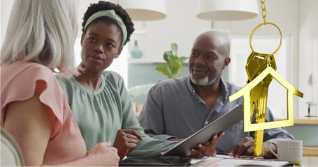 Image of gold house key over diverse couple with female financial advisor in kitchen