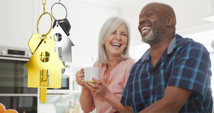 Image of gold house key over diverse couple smiling in kitchen