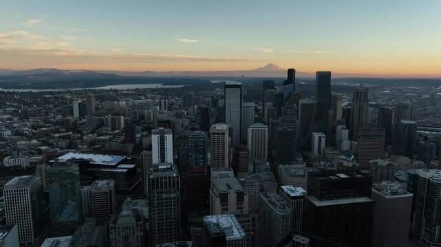 Aerial pan across Seattle cityscape at dusk with Mount Rainer on the horizon