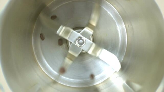 Coffee grinder grinds coffee beans. Slow-motion video.
Slow motion close up shot of roasted coffee beans being ground into finer particles in a coffee grinder
