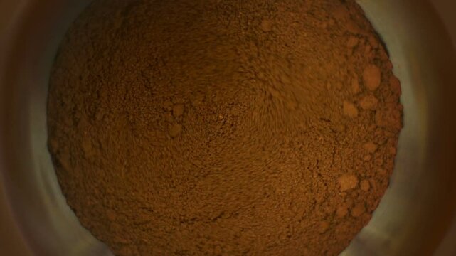 Coffee grinder grinds coffee beans. Slow-motion video.
Slow motion close up shot of roasted coffee beans being ground into finer particles in a coffee grinder
