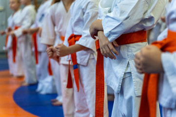 A close-up of a row of young athletes in white karate kimonos with clenched fists.