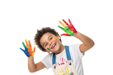 A joyful child, overalls splattered in paint, raises vibrant hands coated in red, yellow, green, and blue paint with a bright smile. Isolated on a transparent background