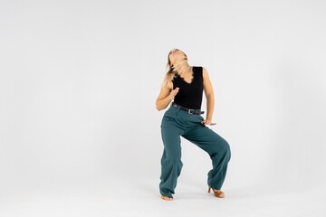 Naklejka premium Young blonde dancer posing with hands joined and legs apart on white background