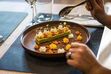 Une assiette contenant un dessert dans un restaurant gastronomique, une main de femme tien une cuillère pour manger