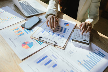 Professional analyzing business charts on laptop in modern office, focusing on planning and strategy, working on investments, growth and marketing alongside technology and documentation.