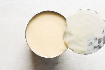 Overhead view of an opened tin of condensed milk with the lid, top view of canned condensed milk