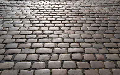Pavement road. Background of bricks road. Stone cladding pavement. Brick surface background. Rough brick road. Cobblestone pavement background. Textured background. Sidewalk. Old cobblestone road.