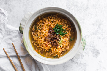 Overhead view of Spicy vegetable instant noodles in a claypot, top view of veggie ramen noodles with broth in a donabe