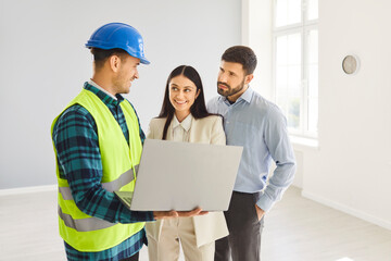Family couple clients meets with a builder or contractor, examining a blueprint for a home...