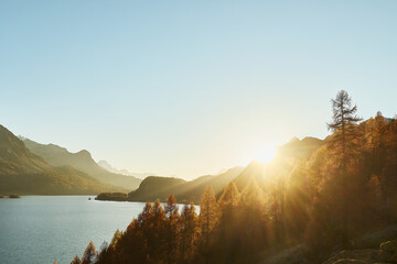 Landschaftsbild mit grossem Bergsee, t&uuml;rkisfarbenem Wasser. Goldene herbst B&auml;ume mit Berg. Letzte Sonnenstrahle von dem Sonnenuntergang