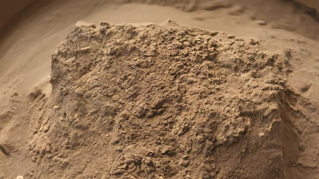 Camera rotates around a sample of clay soil after being worked by hand, the soft light highlights the smooth, molded surface