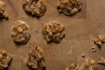 Overhead view of nigerian coconut candy on a wood countertop, top view of candied coconuts discs, flatlay of bukayo candy or coconut drops