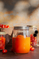 homemade tomatoes sauce in a glass bottle jar on brown rustic table.