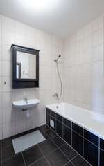 Modern Home Interior Bathroom with Bathtub and Washbasin in Neutral Tones. Clean and simple bathroom interior featuring a white bathtub, wall-mounted sink, and neutral tiles.
