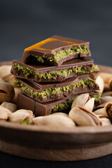 Dubai chocolate with pistachios and kadaif in wooden plate.