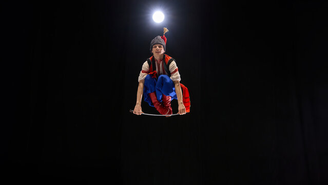 Dancer airborne with traditional sabre, costume adorned with embroidery, expressing warrior spirit through elegant yet powerful motion. Concept of traditions, folk style, art and history. Ad