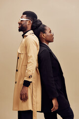 Stylish urban couple in fashionable outfits against a neutral background, showcasing elegance and...