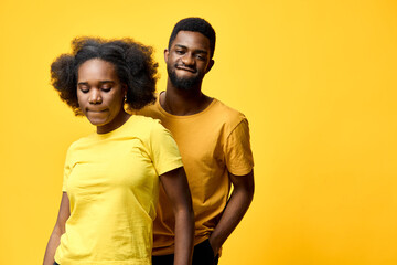 Obraz premium Young couple posing in matching yellow outfits against a vibrant yellow background, conveying joy and harmony in a cheerful, seasonal setting