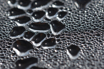 Close-up view of water condensation on a surface creating intricate patterns and shapes in a cool, dimly lit environment