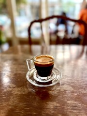 Espresso shot in glass cup on wooden table at cafe shop