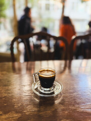 Espresso shot in glass cup on wooden table at cafe shop